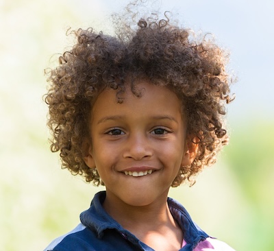 child with curly hair smiling